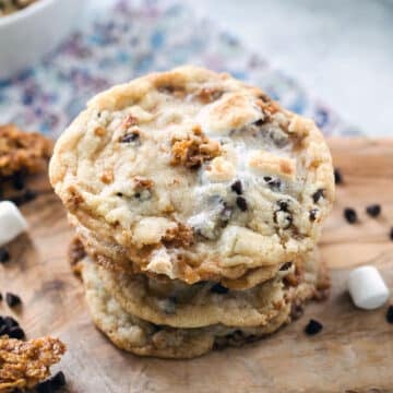 Stack of cornflake chocolate chip marshmallow cookies on a wooden board.