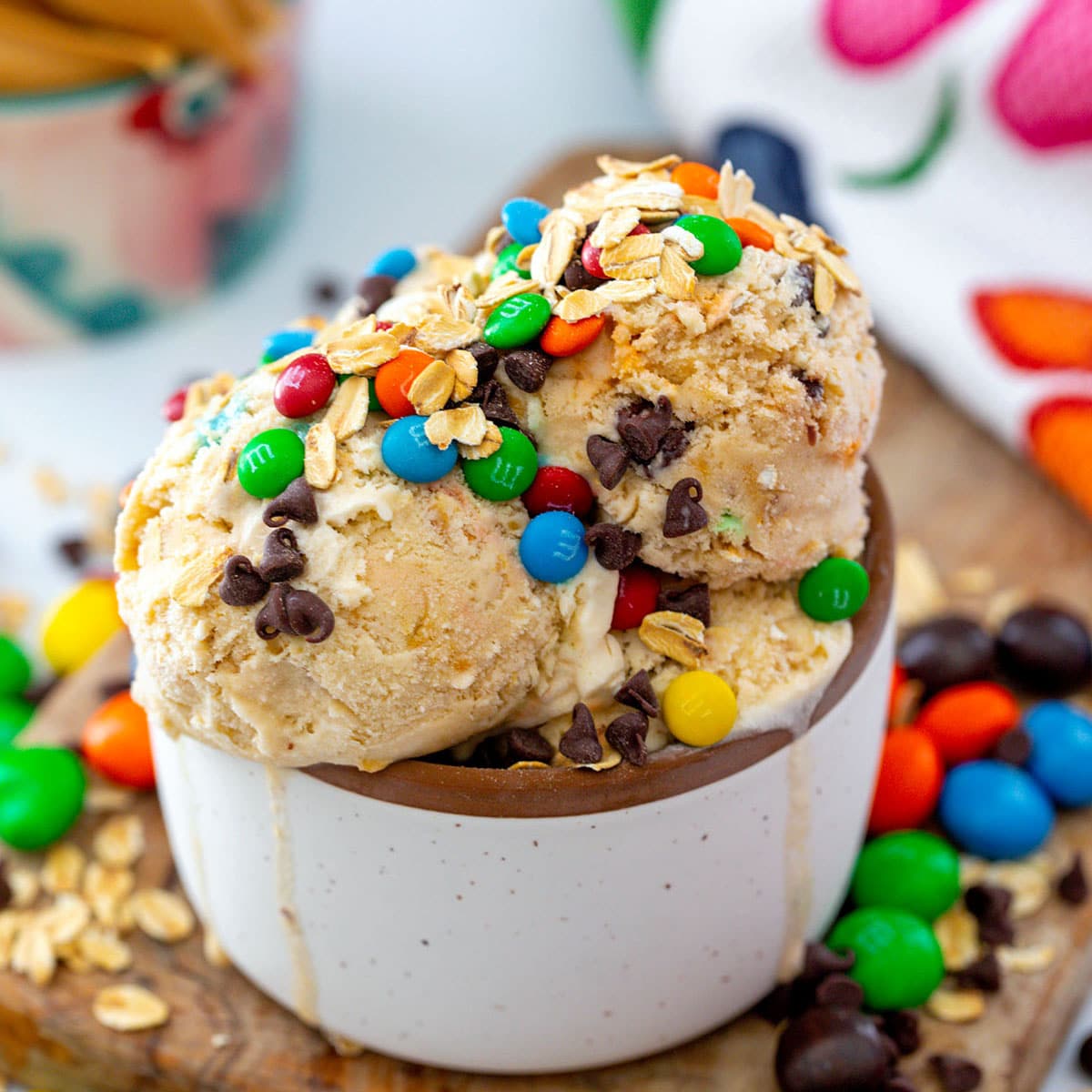 Monster cookie ice cream in a bowl topped with M&Ms, oats, and chocolate chips.