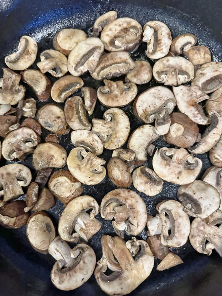 Sliced mushrooms in cast iron skillet.