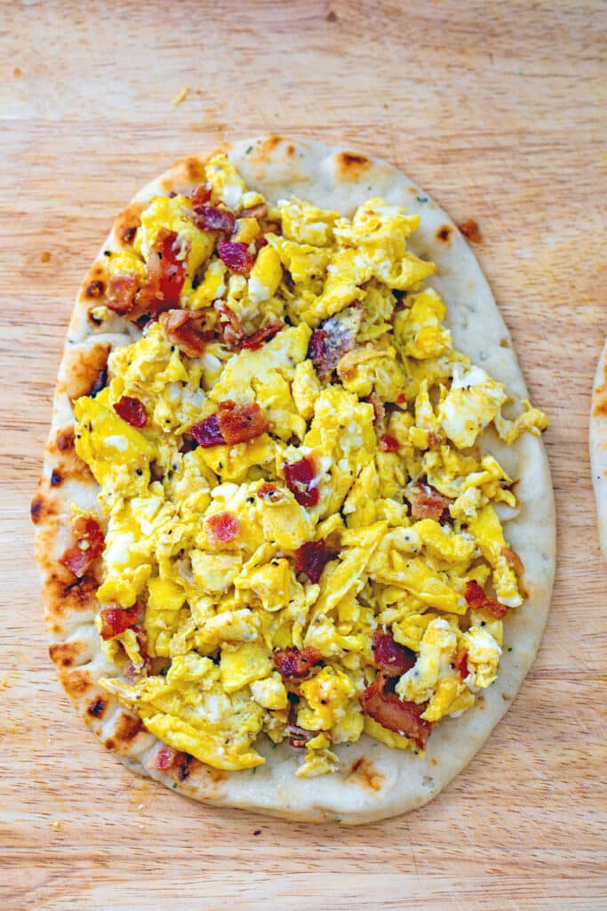 Scrambled eggs and crumbled bacon on naan round.