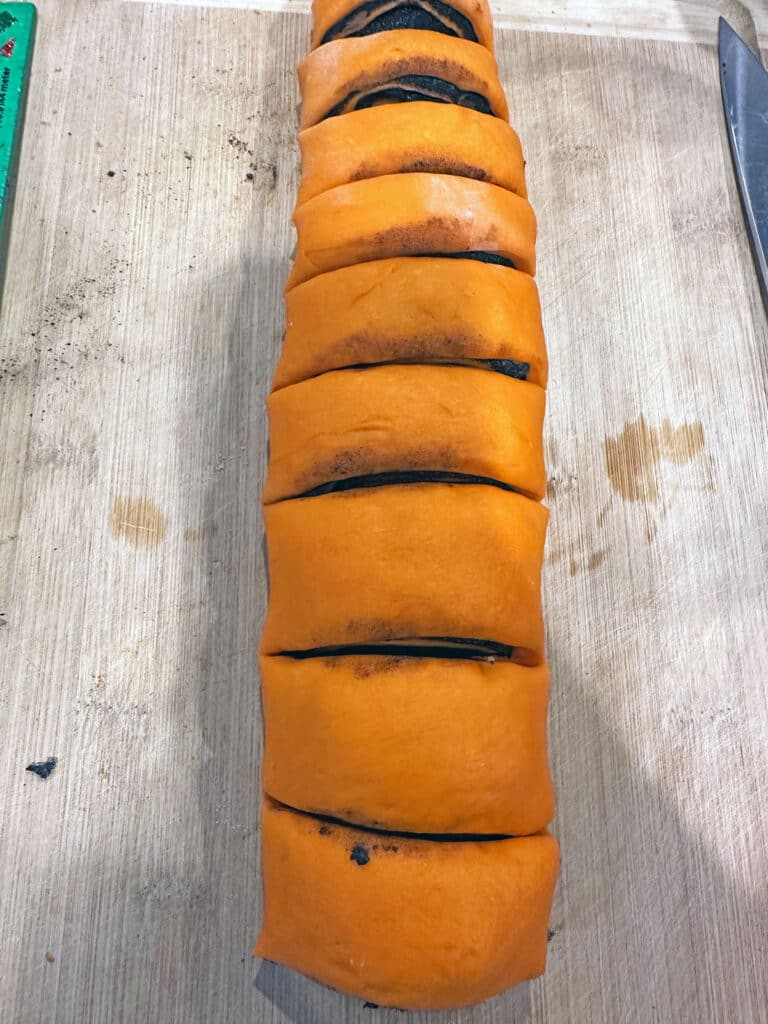 Orange cinnamon bun dough rolled up and sliced.