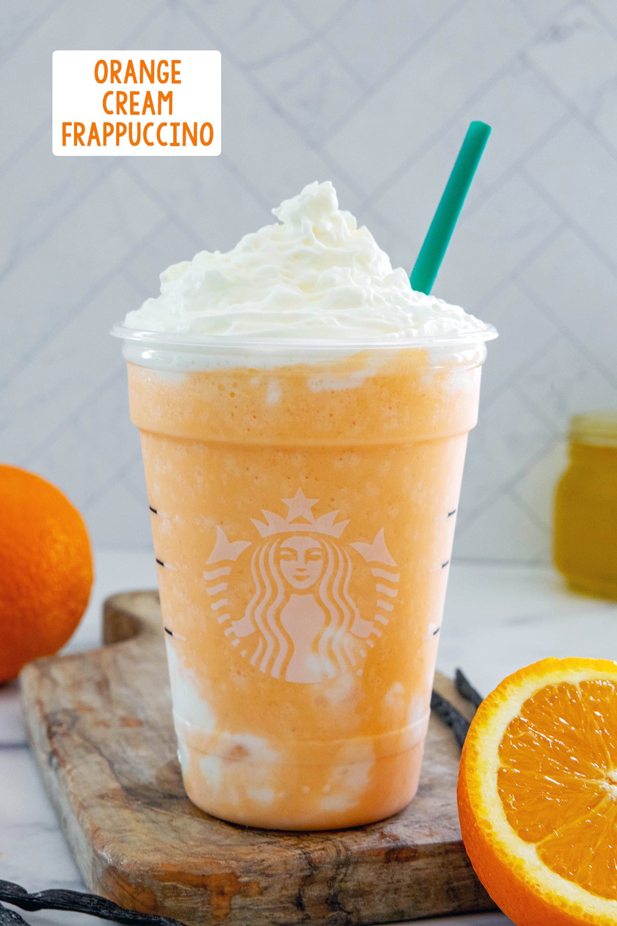 Head-on view of an Orange Frappuccino in a Starbucks cup with oranges all around and recipe title at top.