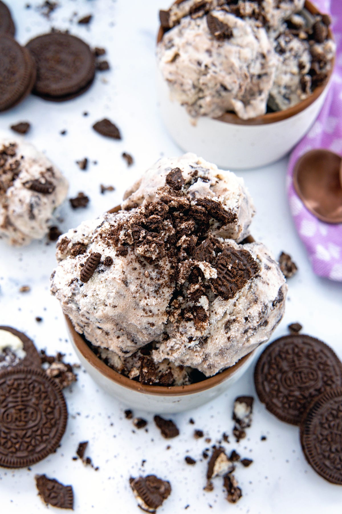 Overhead view of two bowls of Oreo ice cream with crushed and whole Oreo cookies all around.