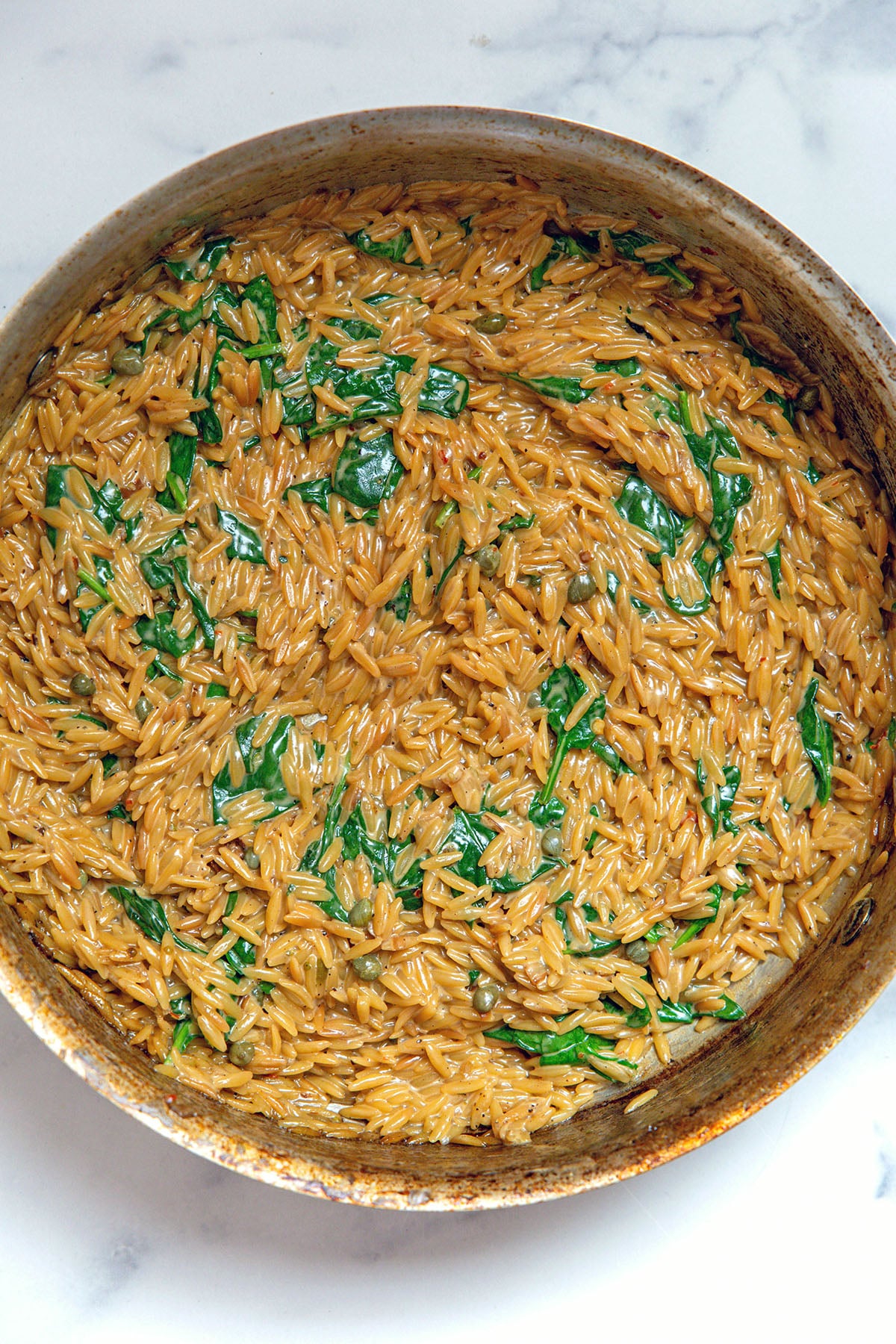 Creamy orzo and spinach in skillet.