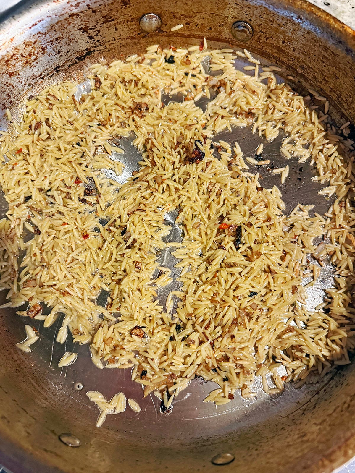 Orzo toasting in skillet.