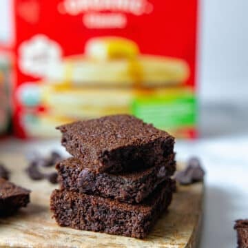 Closeup view of a stack of chocolate brownies with box of pancake mix in background.
