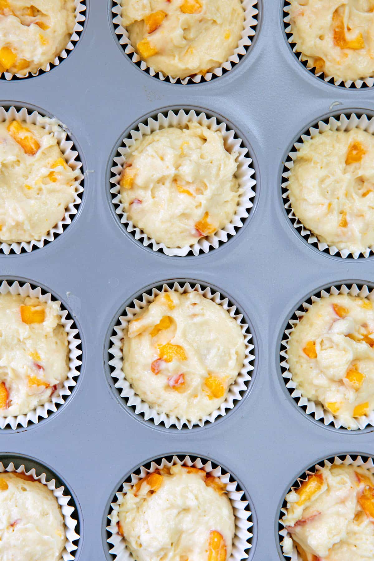 Peach cupcake batter in baking tin.