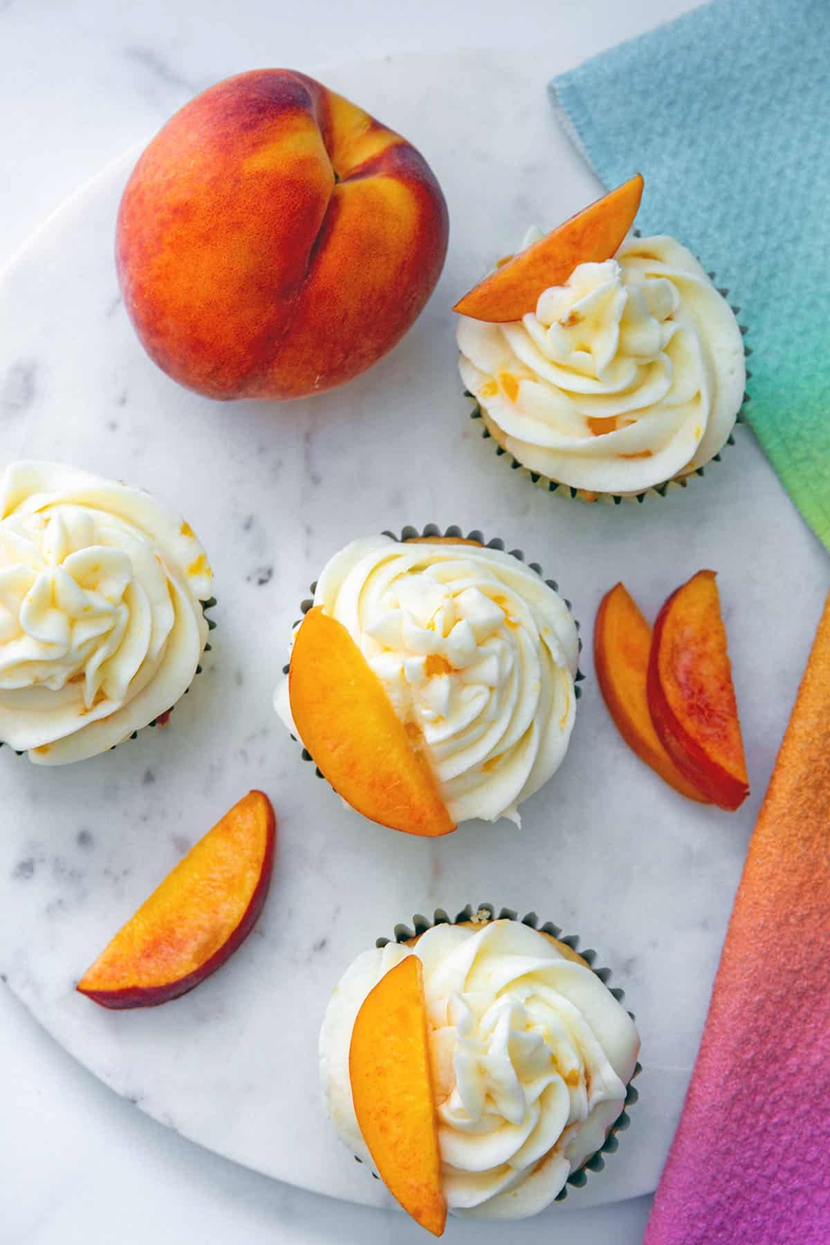 Overhead view of peach cupcakes in marble platter.
