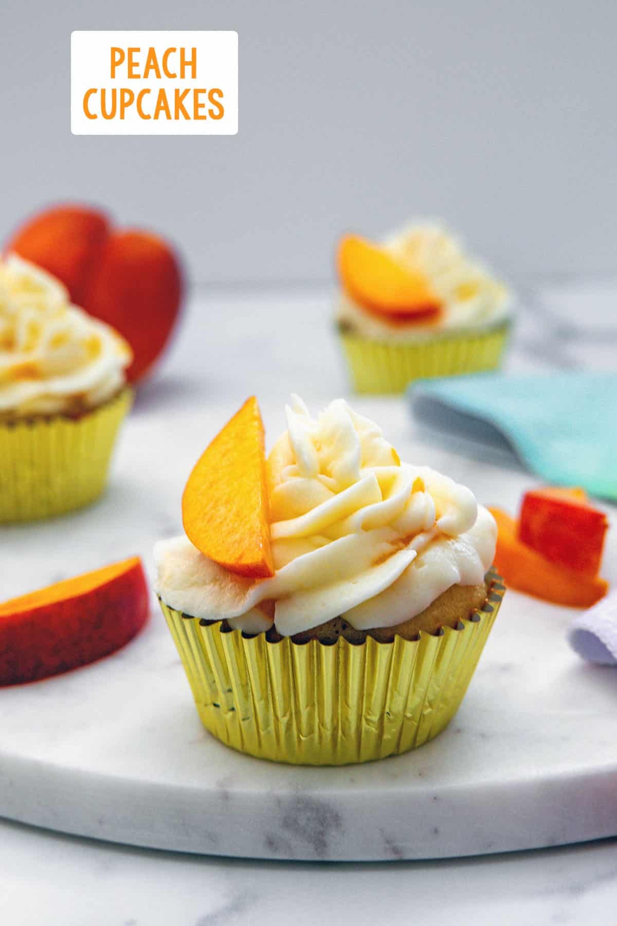 Head-on view of a peach cupcake with more in background, peach slices all round, and recipe title at top.