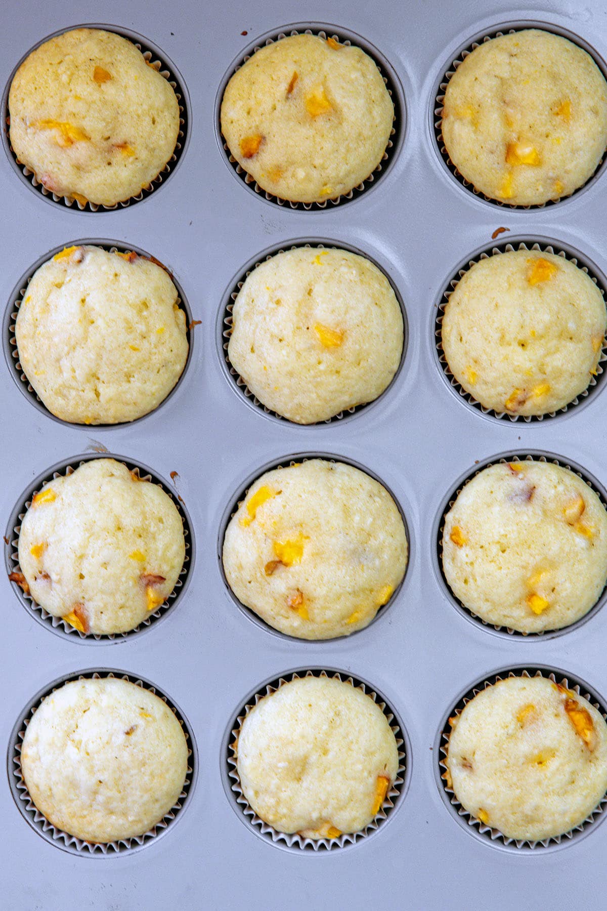 Peach cupcakes baked in a cupcake tin.