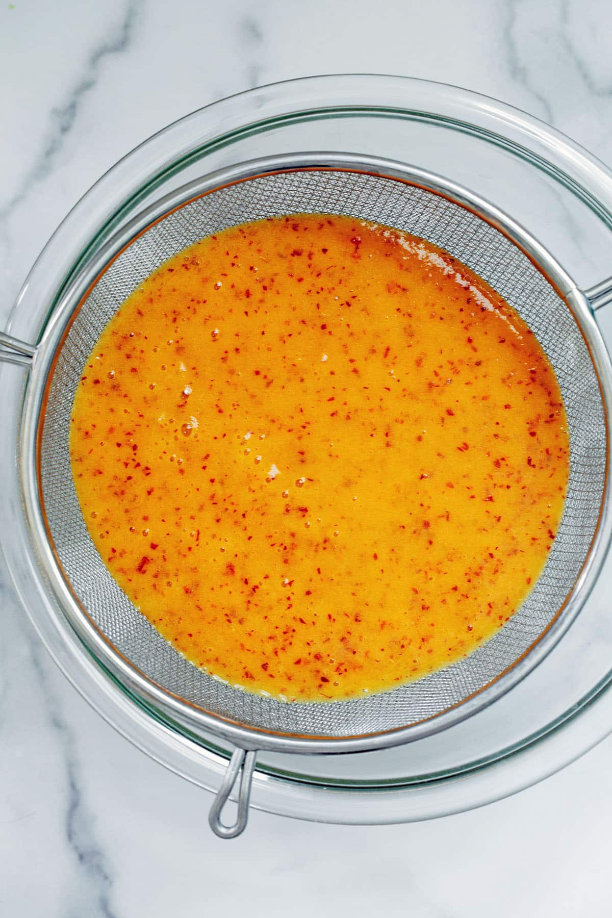 Peach nectar being strained into bowl.