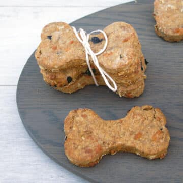 Closeup view of a peanut butter cheddar dog bone with stack of bones in background.