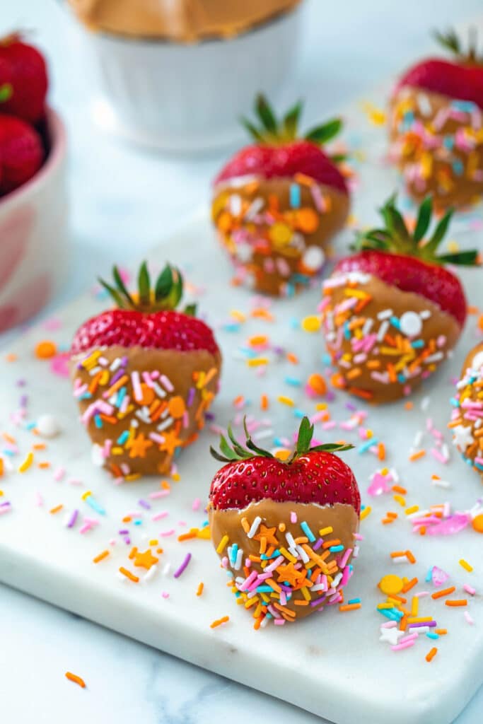 Marble platter with peanut butter-dipped strawberries with sprinkles.