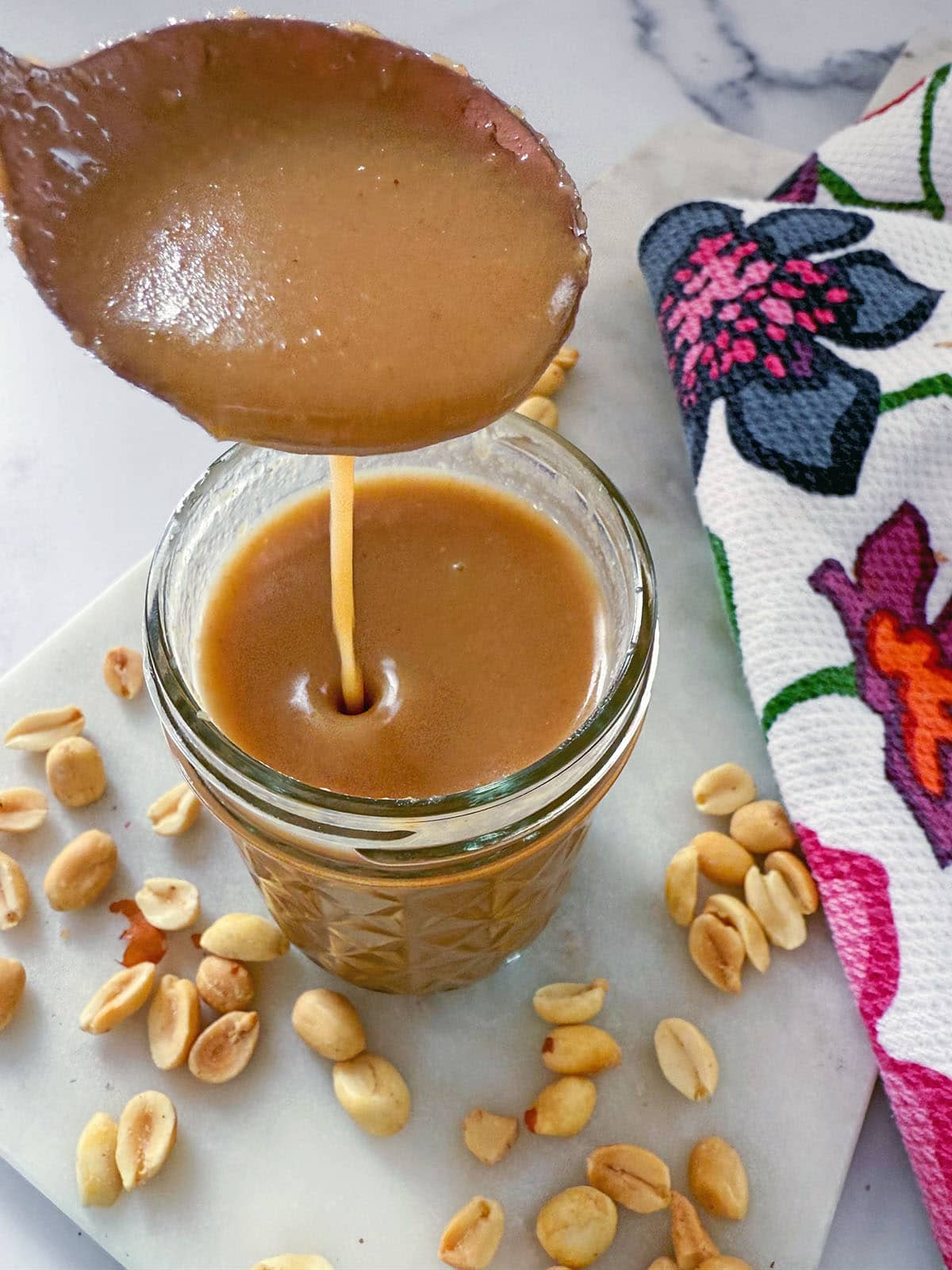 Close-up view of peanut butter syrup dripping off a spoon.