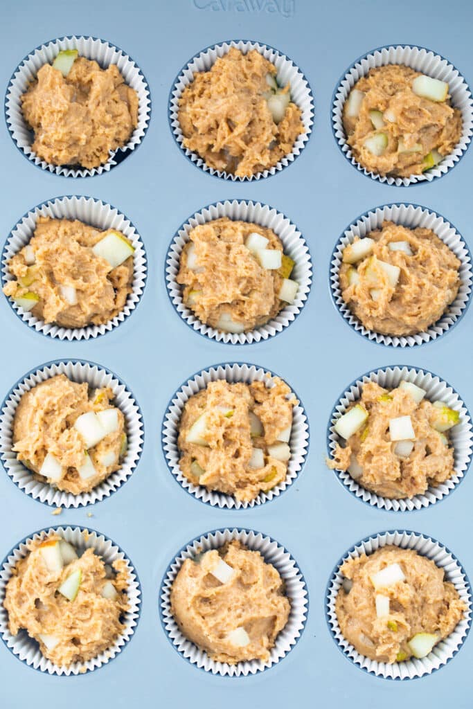 Overhead view of muffin tin filled with pear batter.