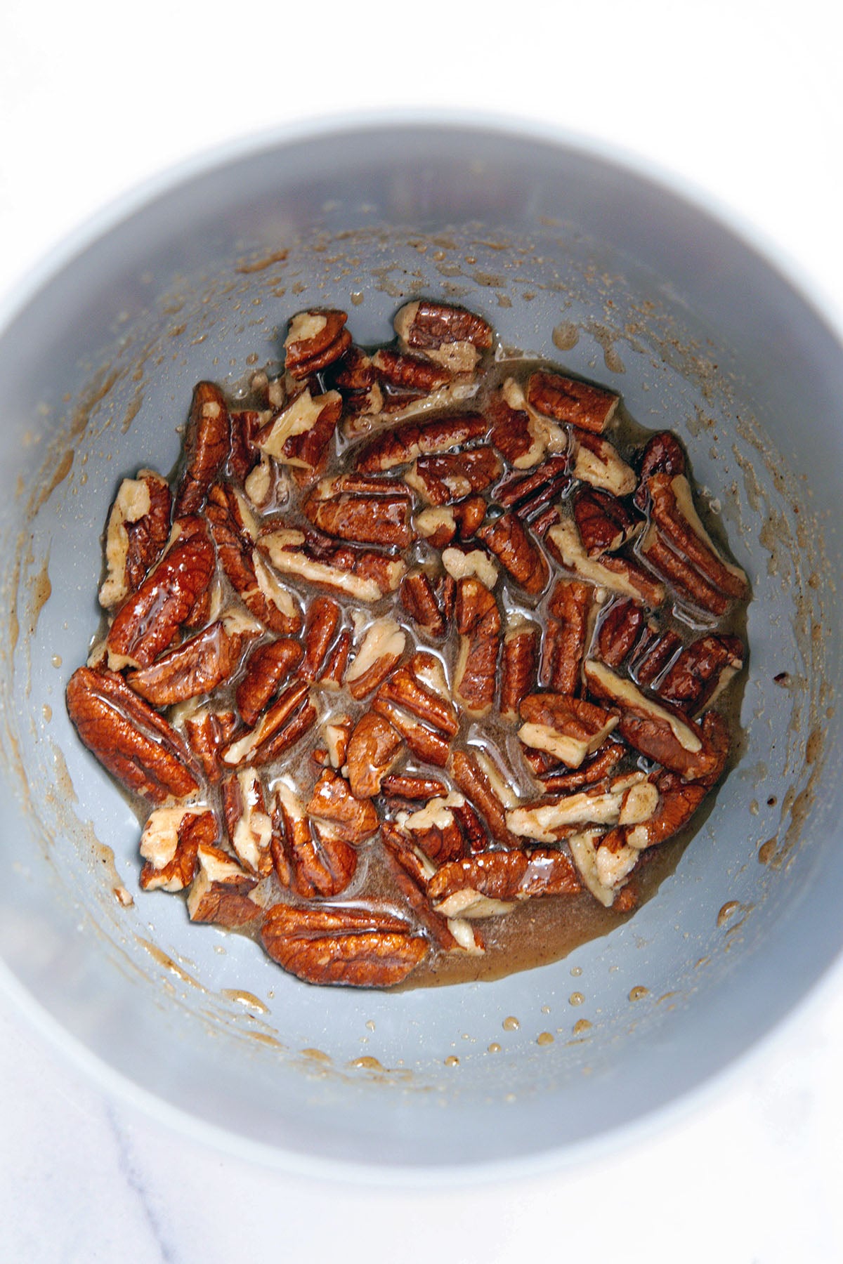 Pecans in sugar mixture in saucepan.
