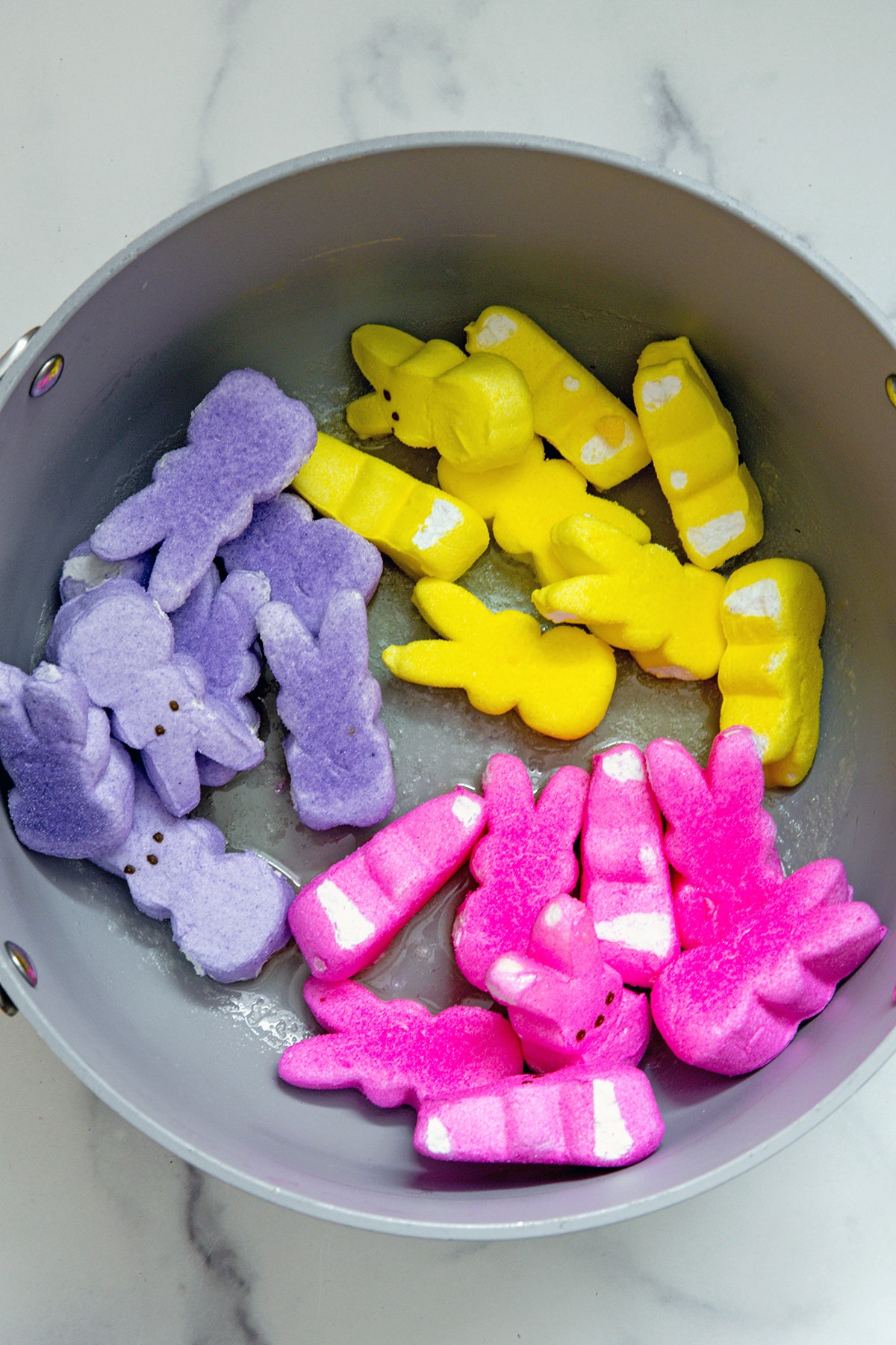 Pink, purple, and yellow Peeps bunnies in saucepan.