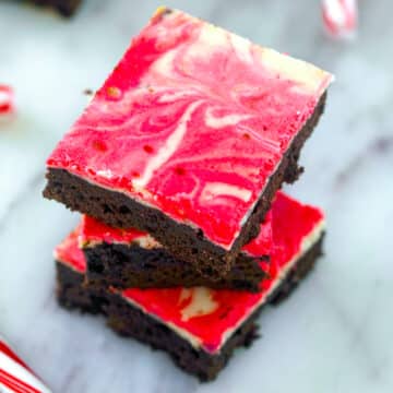 Stack of red and white swirled peppermint cheesecake brownies.