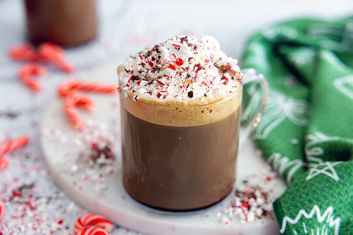 Landscape overhead view of a Peppermint Mocha topped with whipped cream, chocolate shavings, and candy cane pieces.