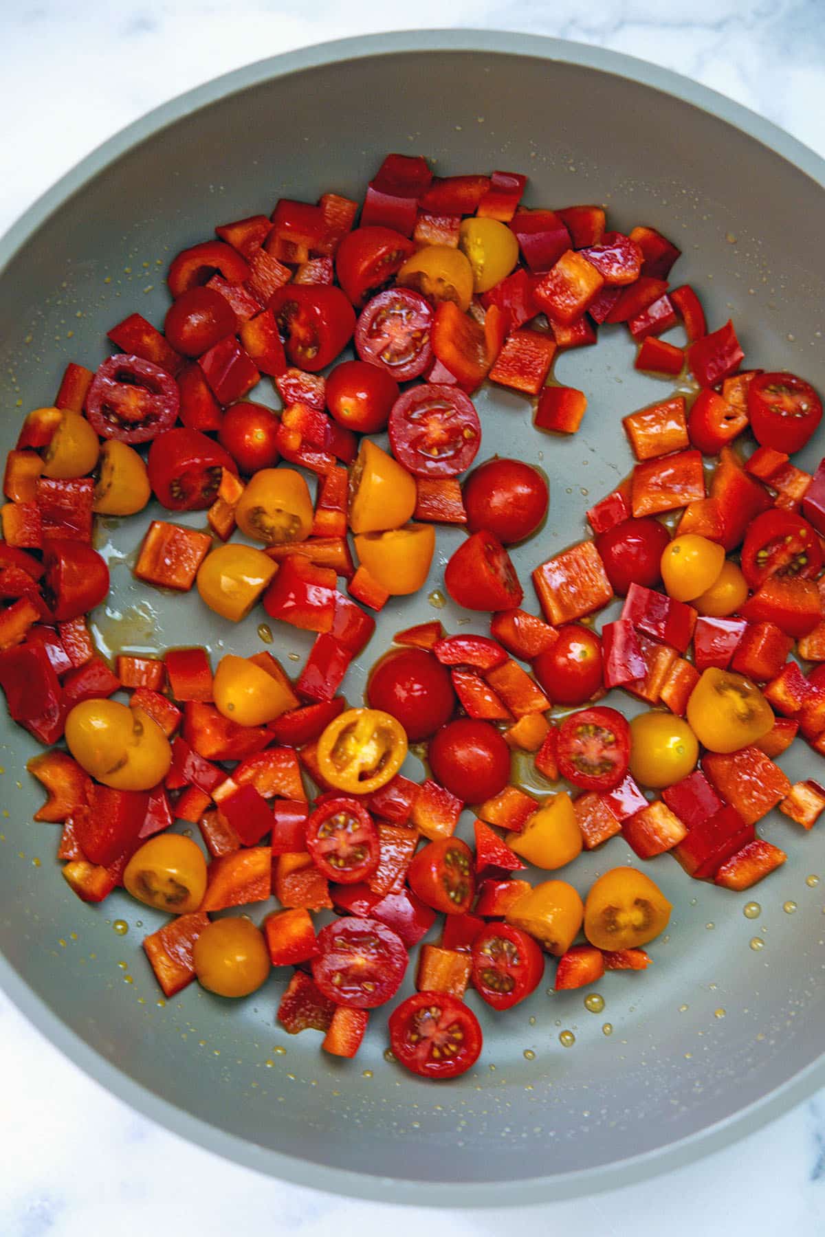 Tomatoes and red peppers cooking in skillet.