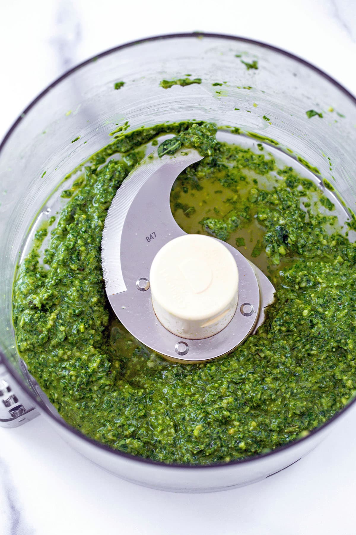Pesto with olive oil in food processor bowl.