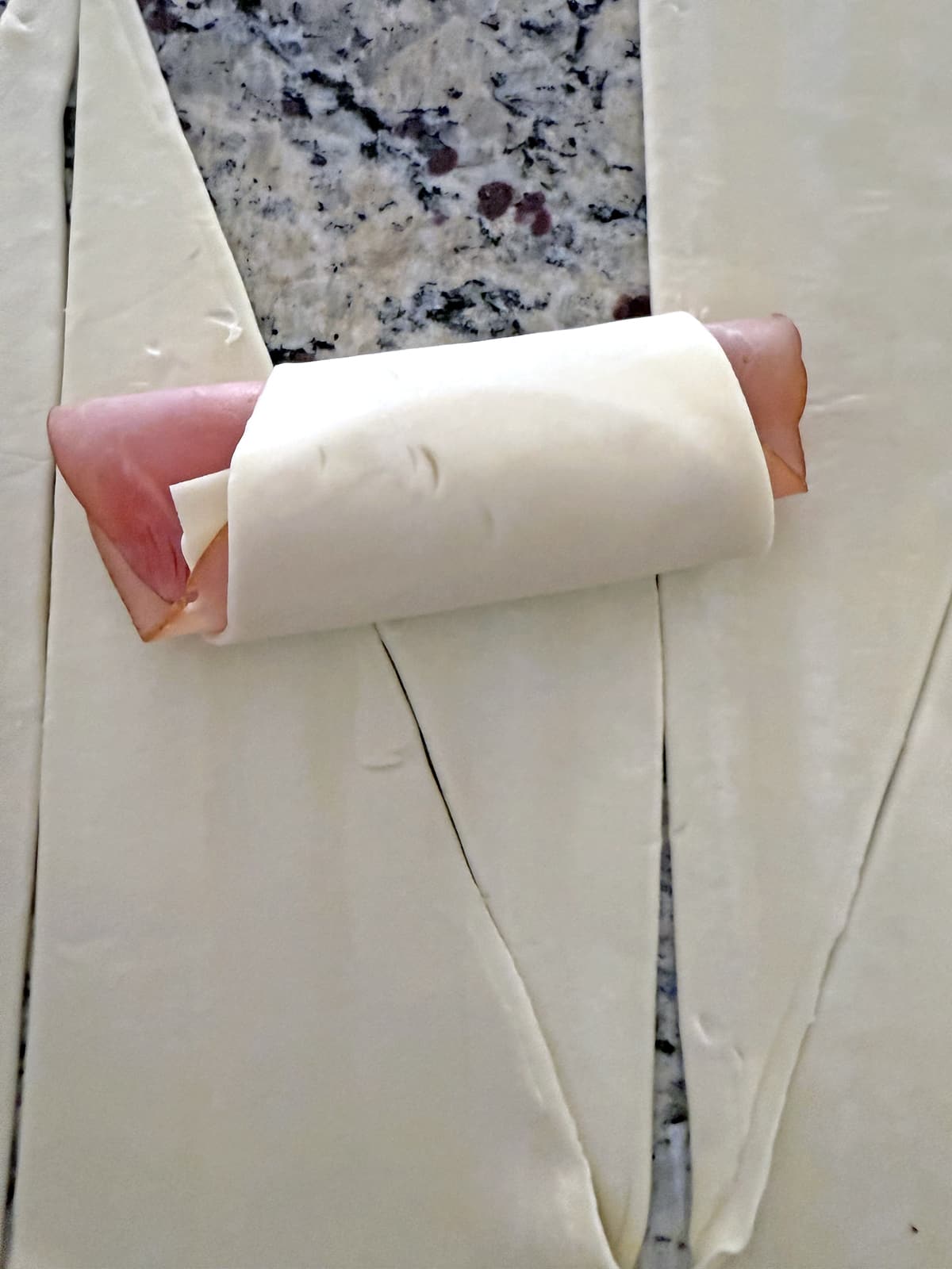 Phyllo dough triangle with ham and swiss rolled down.
