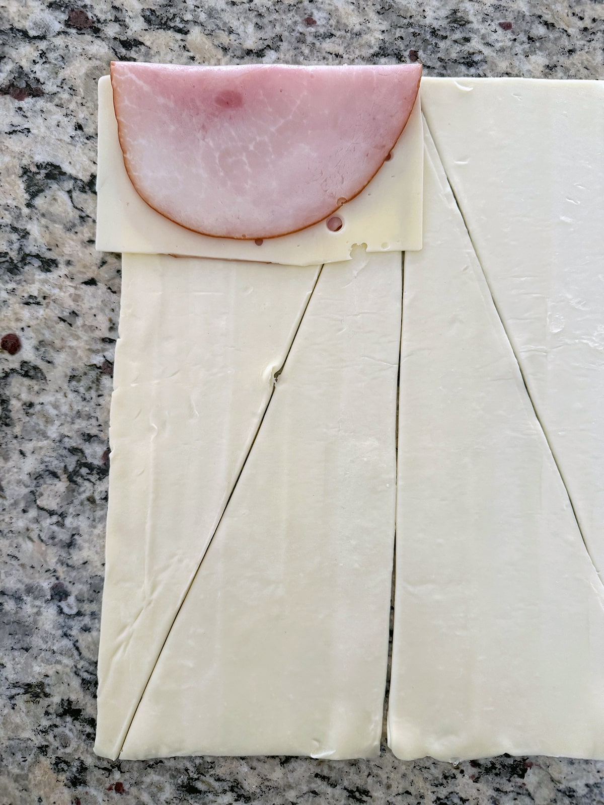 Slice of cheese and ham at the top of a triangle of phyllo dough.