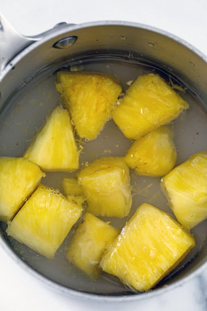 Chopped pineapple in saucepan with water and sugar.