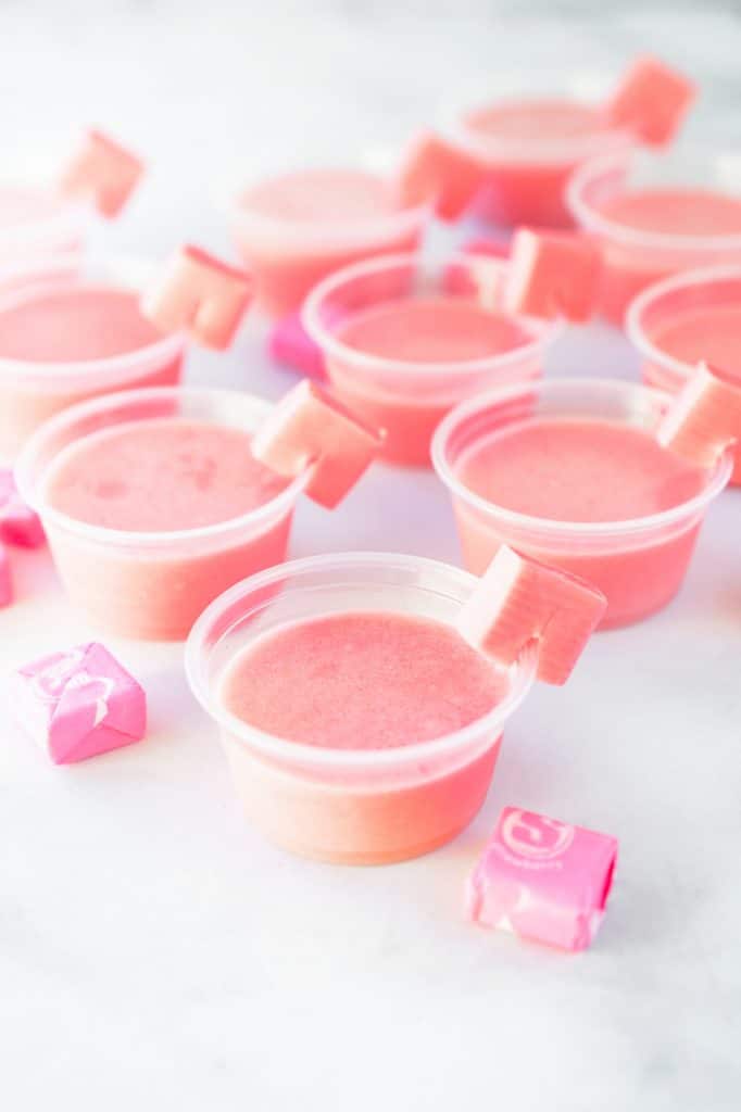 Multiple pink Starburst jello shots in little cups with Starburst garnish