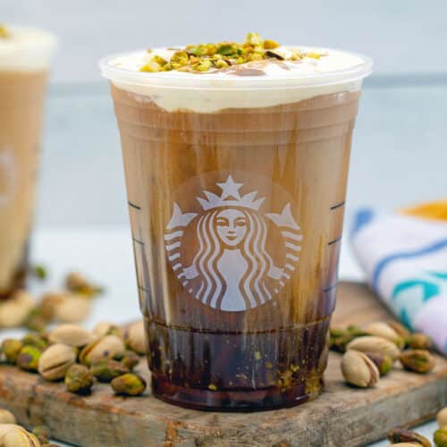 Pistachio cream cold brew in a Starbucks cup with pistachios all around.