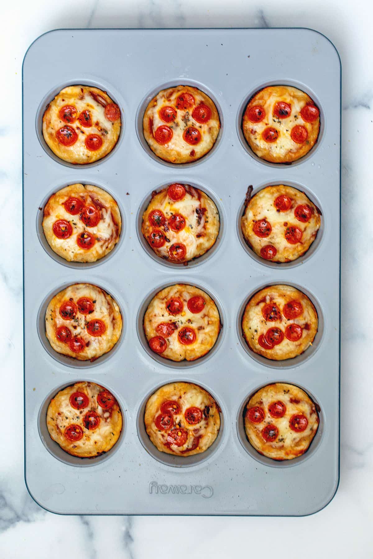 Pizza cupcakes in tin just out of the oven.