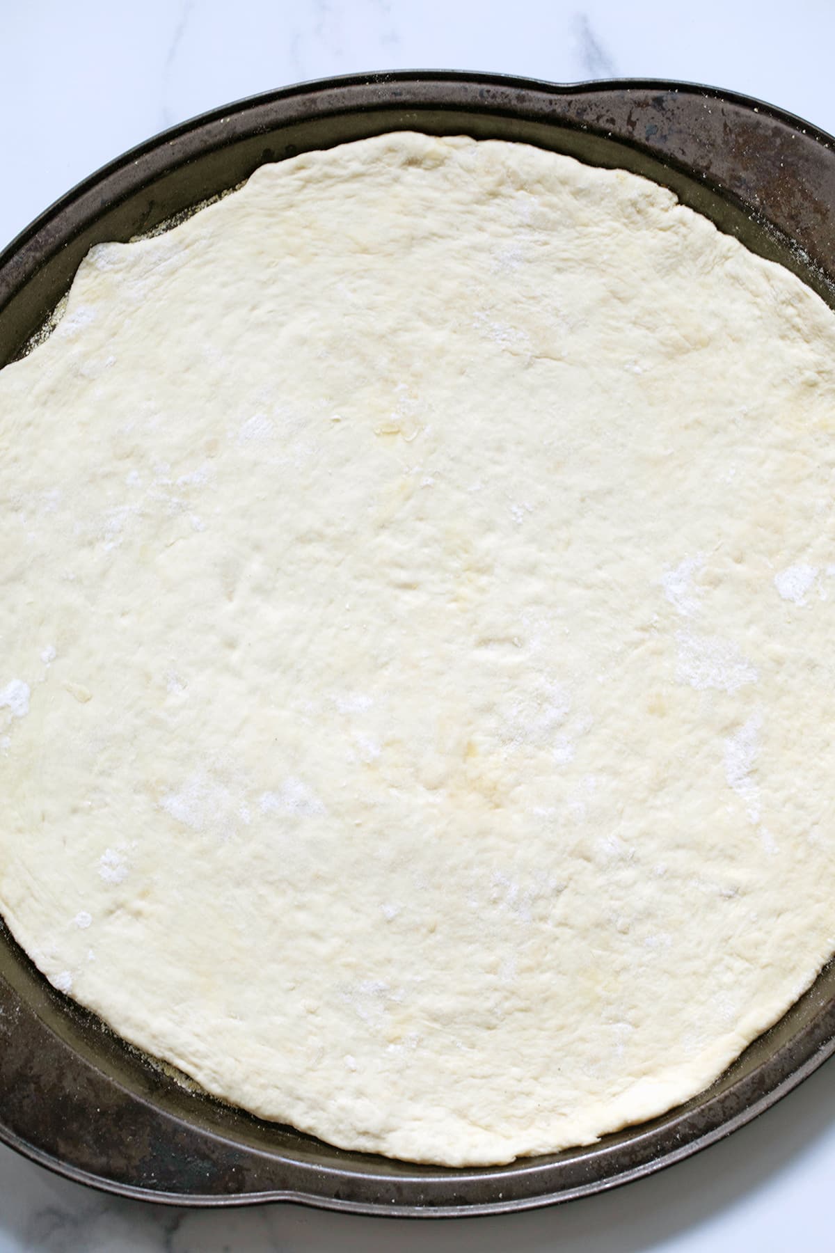 Pizza dough rolled out in pan.