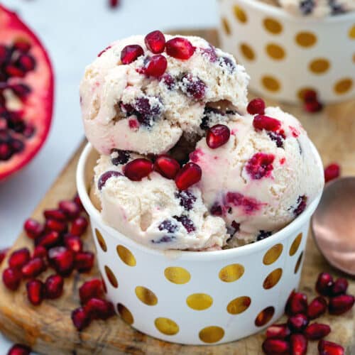 Closeup overhead view of pomegranate ice cream with seeds on top and all around dish.