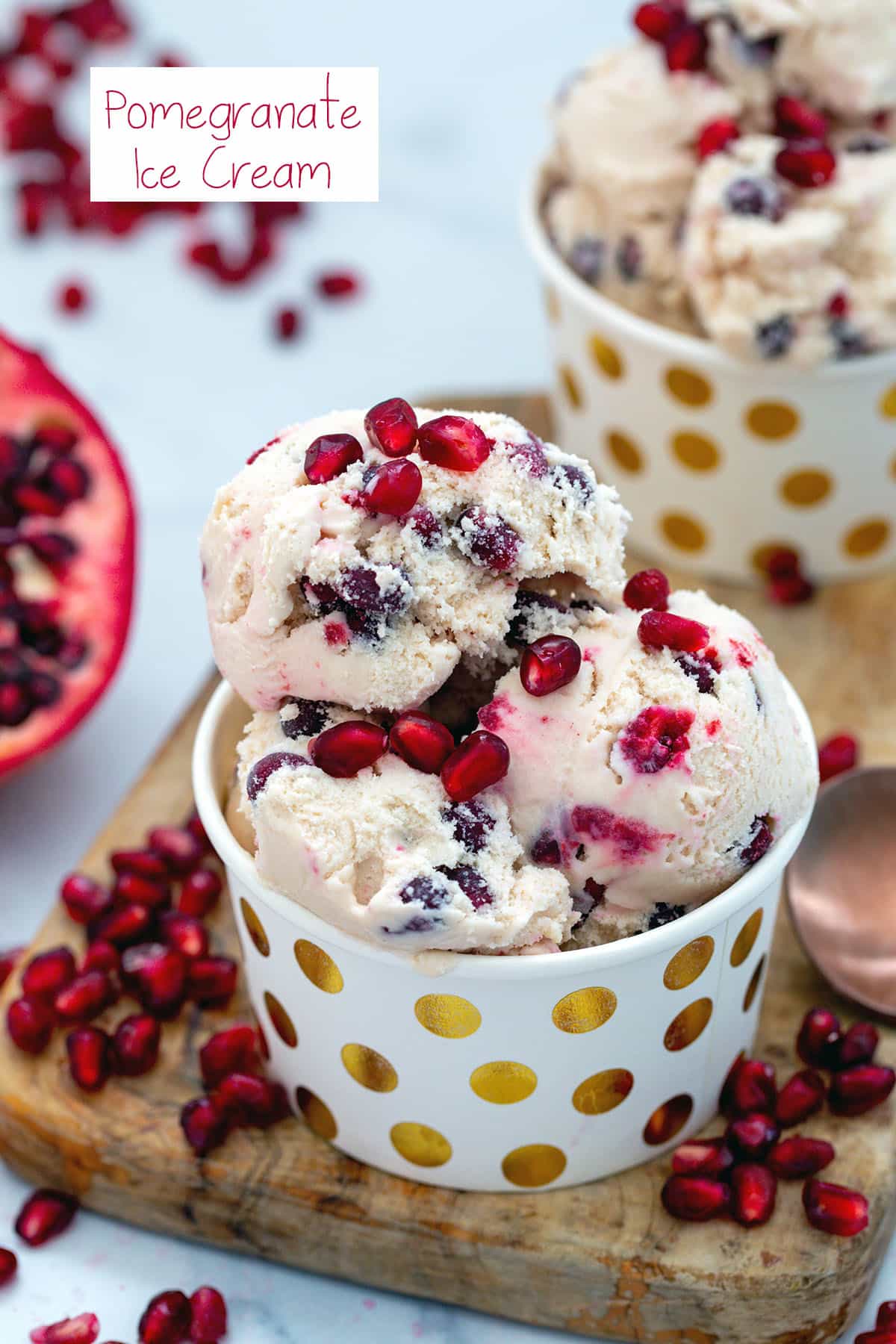 Bowl of pomegranate ice cream with pomegranate half and arils in background and recipe title at top.