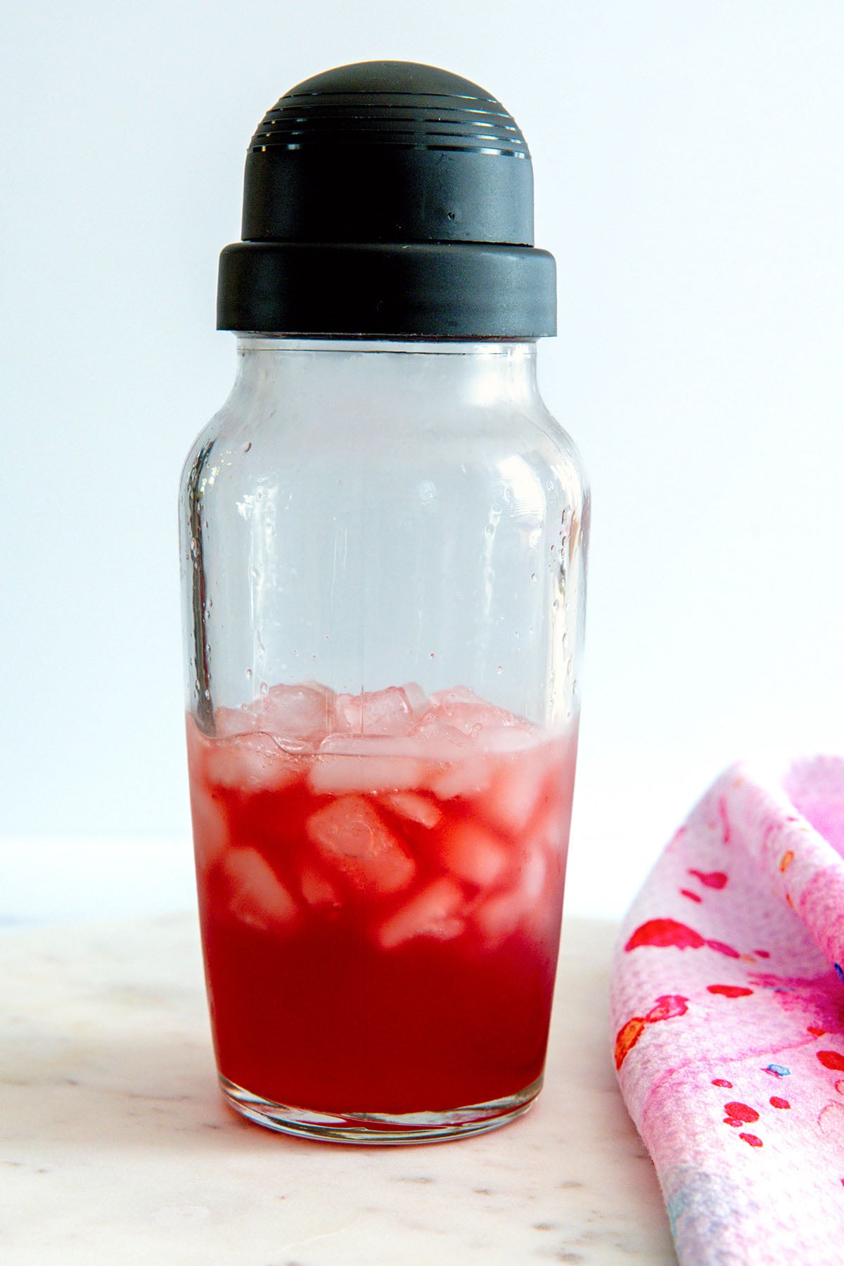 Head-on view of a pomegranate margarita mixture in a clear shaker.