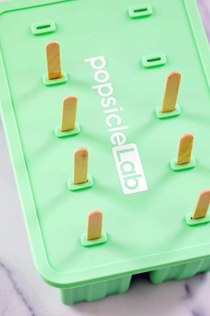 Popsicle molds with popsicle sticks sticking out.