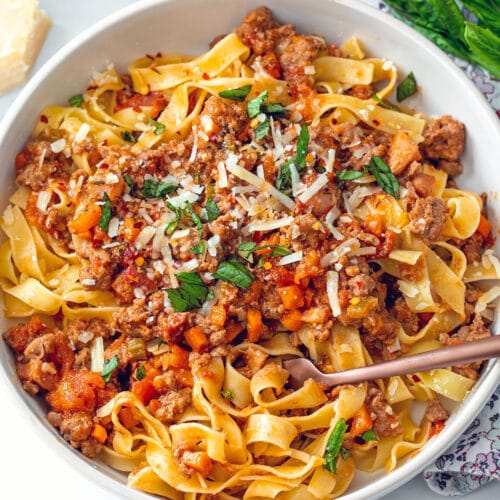 Closeup view of pork bolognese with fork in dish.