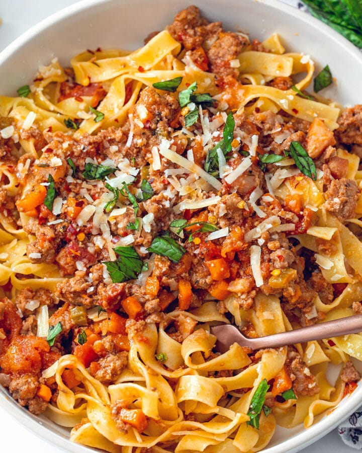 Closeup view of pork bolognese with fork in dish.