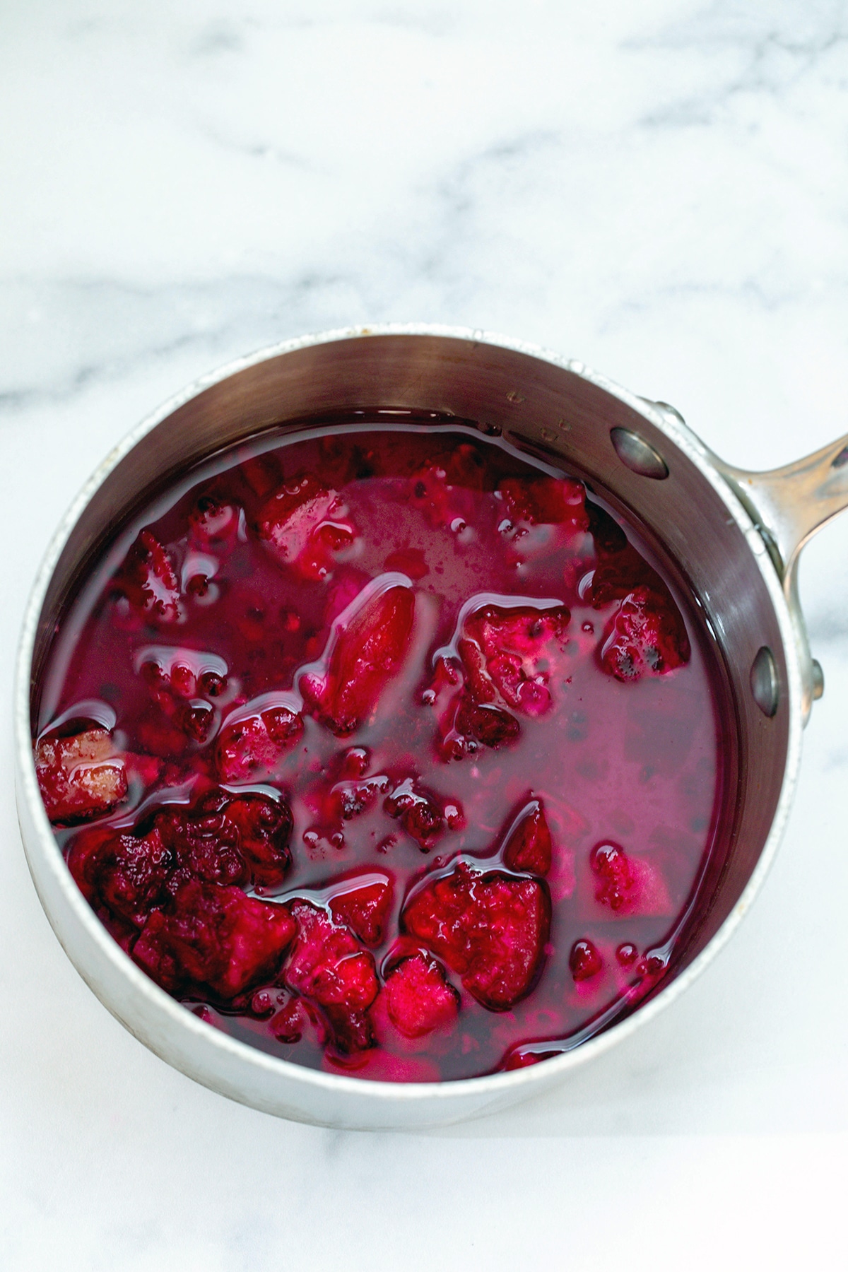 Chopped prickly pears in saucepan with water and sugar.