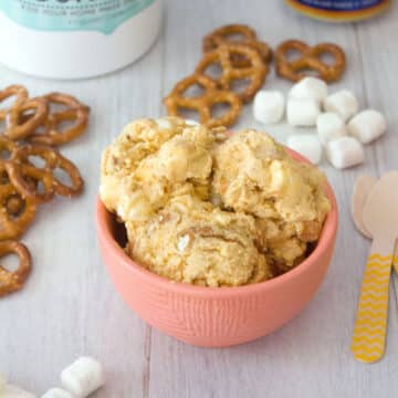Closeup view of a bowl of pumpkin beer ice cream with pretzels and mini marshmallows in background.