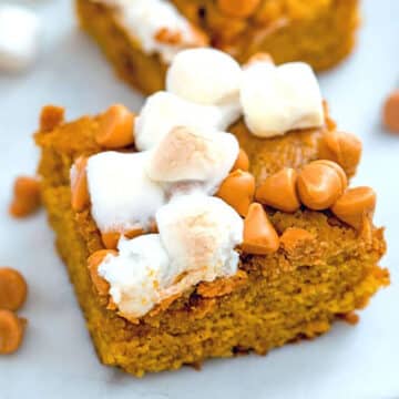 Closeup view of a pumpkin butterscotch blondie with mini marshmallows on top.