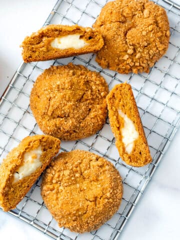 Overhead closeup view of multiple pumpkin cheesecake cookies, some cut in half to show cream cheese filling.