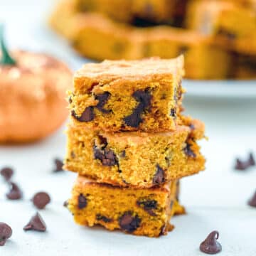 Closeup view of a stack of pumpkin chocolate chip squares with chocolate chips all around.