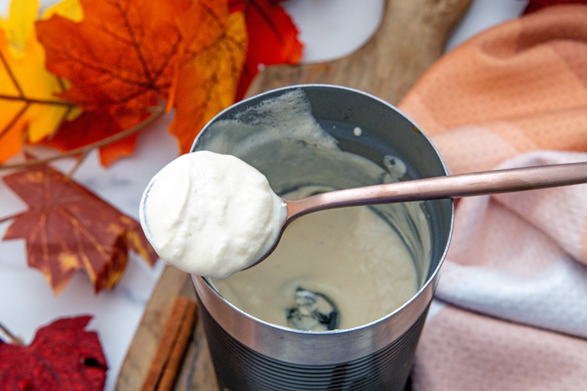 Pumpkin cold foam on spoon over frother.