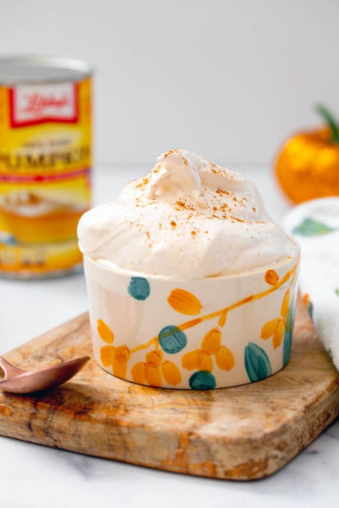 Pumpkin fluff in a small bowl with can of pumpkin puree in background.