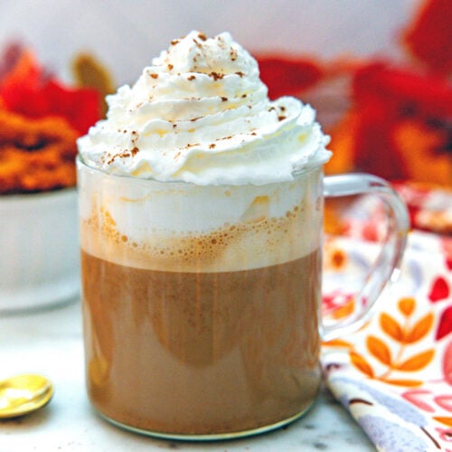 Closeup view of a pumpkin spice latte topped with whipped cream and pumpkin pie spice.