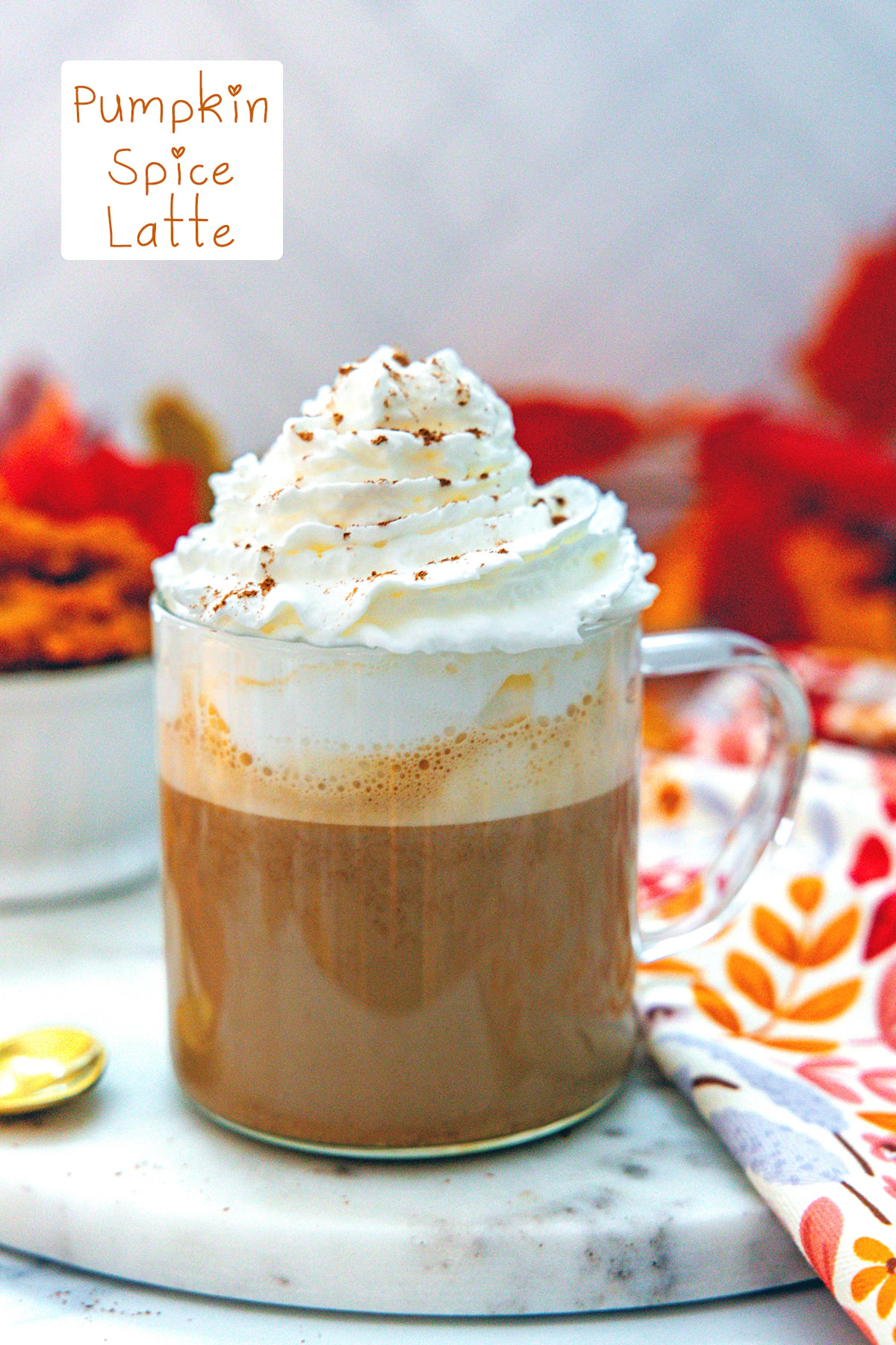 Head-on view of a pumpkin spice latte topped with whipped cream with recipe title at top.
