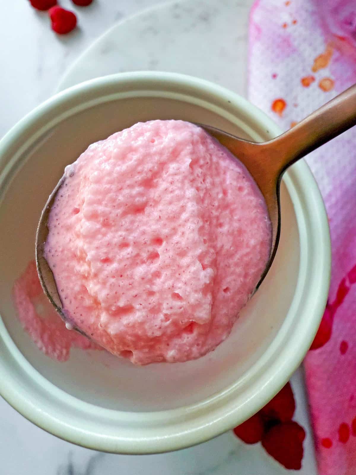 Overhead view of raspberry cold foam on a spoon.