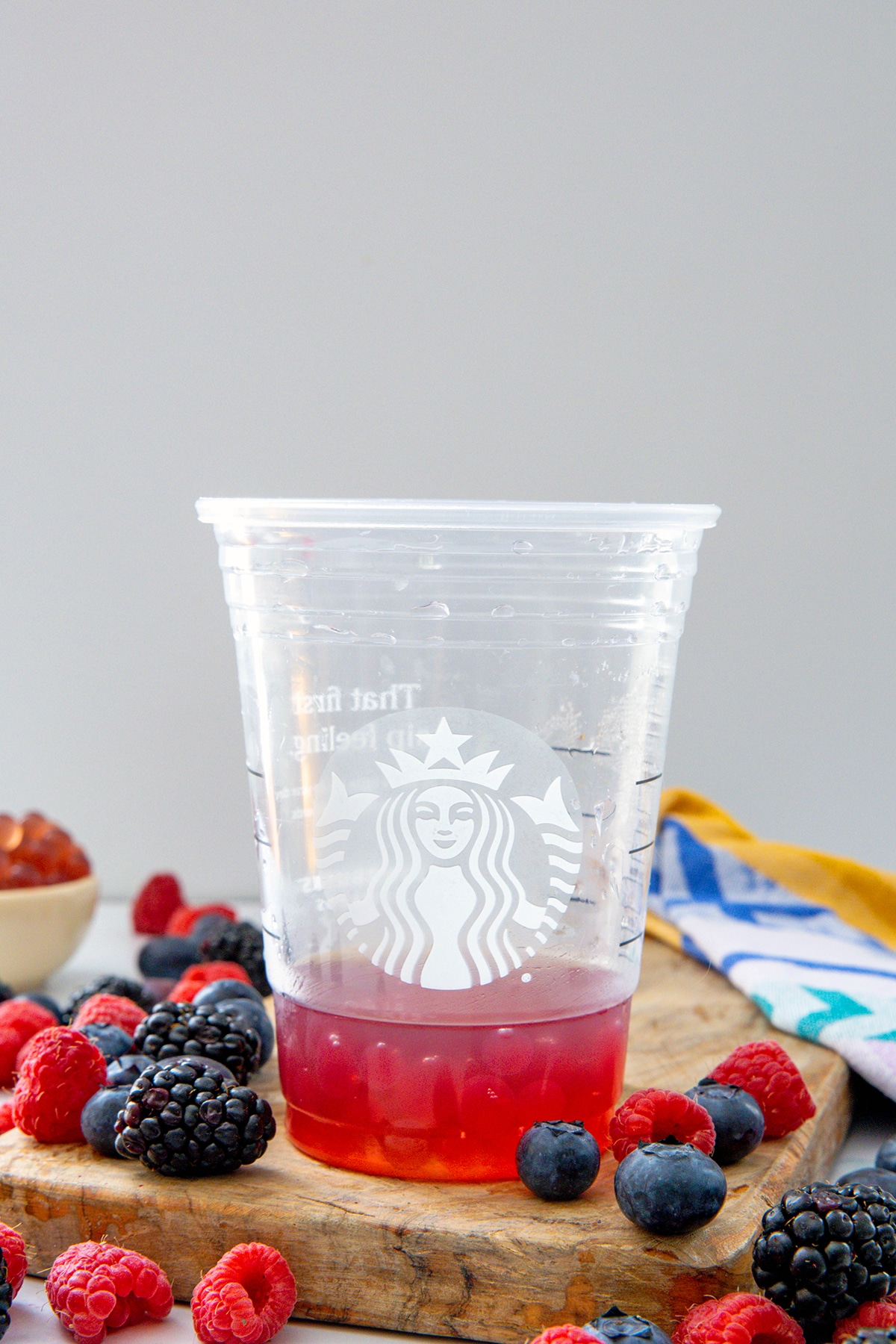 Starbucks cup with raspberry pearls in it and fresh berries all around.