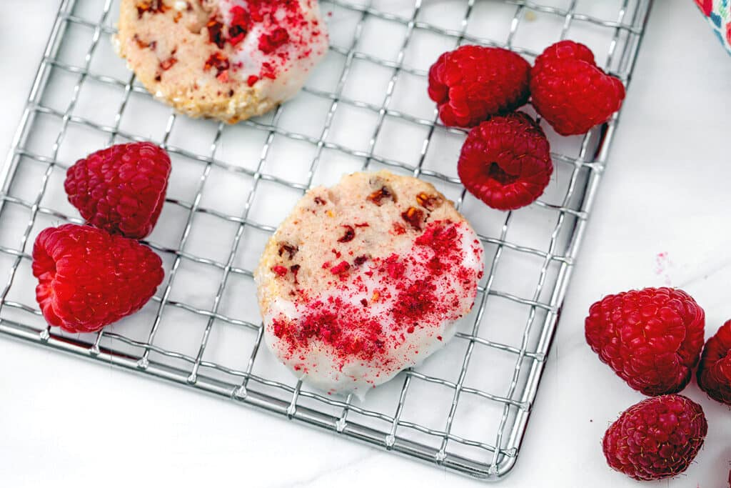 Overhead view of raspberry shortbread cookie on baking rack with raspberries.